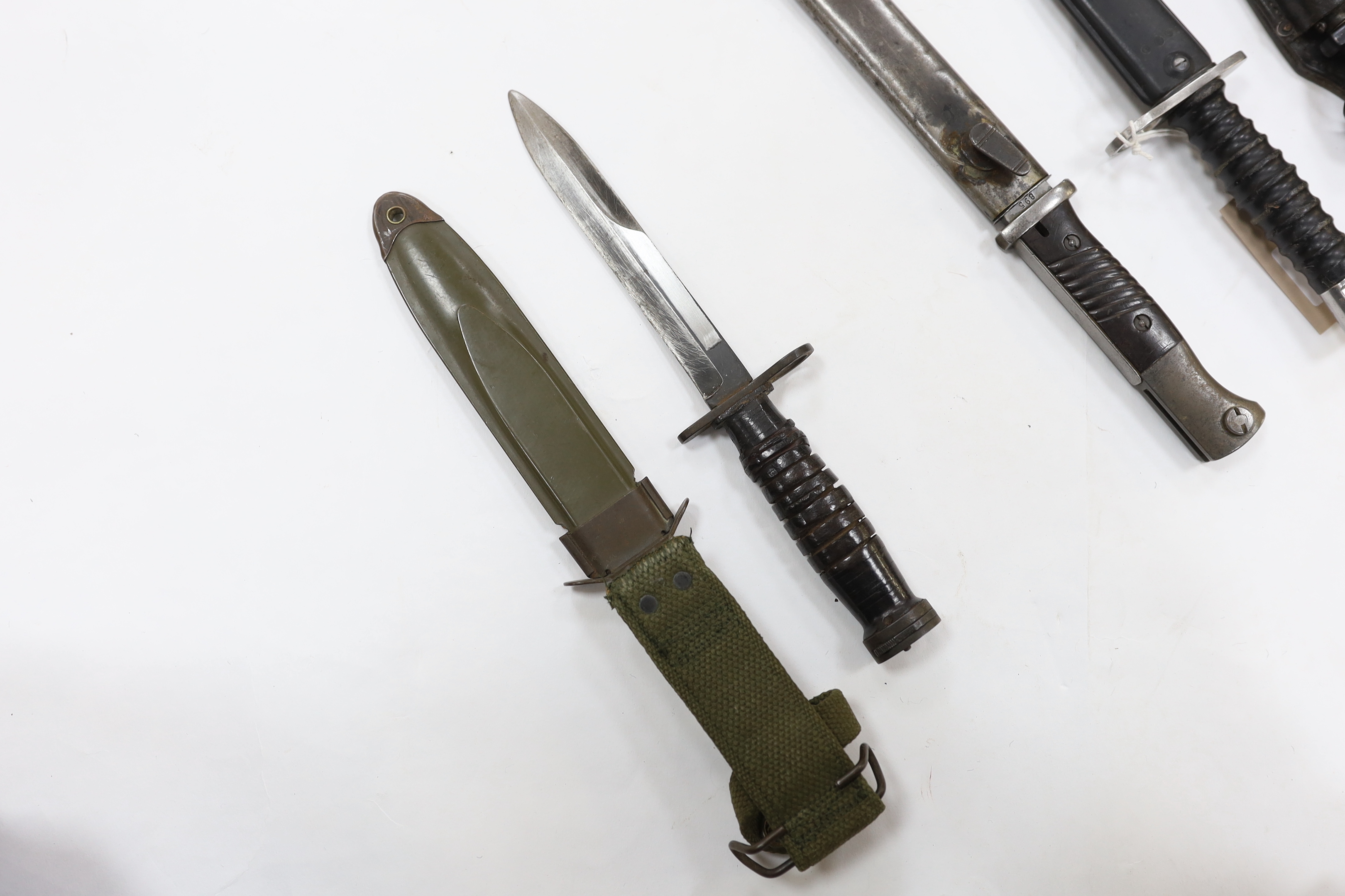 Four bayonets; two Mauser bayonets in scabbards, an American M8A1 carbine bayonet in a scabbard, and another